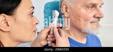 Hörtest bei Reifen Menschen, Otoskopie. HNO-Arzt, der das Ohr des älteren Mannes mit Otoskop oder Vorhofskop im medizinischen Zentrum überprüft Stockfoto