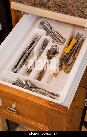 Weißes Kunststofftablett mit Küchenutensilien in geöffneter Holzschublade. Stockfoto