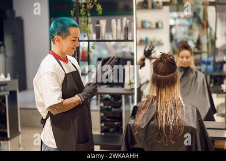Professioneller Kolorist zieht Handschuhe an, bevor er Haare im Schönheitssalon färbt Stockfoto