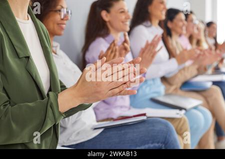 Verschiedene weibliche Unternehmensmitarbeiter sitzen bei Konferenzen oder Geschäftsschulungen und applaudieren. Stockfoto