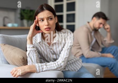 Besorgte junge Frau mit verärgertem Mann im Hintergrund Stockfoto