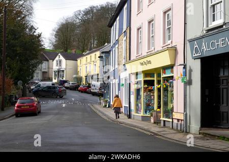 Blick auf eine Frau, die entlang der King Street an einer Reihe von Geschäften in der Stadt Llandeilo Carmarthenshire Wales, Großbritannien KATHY DEWITT, vorbeiläuft Stockfoto