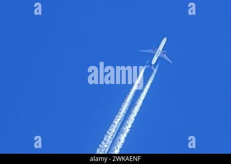 Fliegendes zweimotoriges Jet-Flugzeug / Flugzeug von der Fluggesellschaft Kuwait Airways zeigt Kondensstreifen / Kondensationswege gegen blauen Himmel Stockfoto