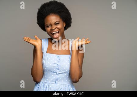 Überglückte schwarze Frau lächelt, lacht breit vor großer Freude glücklich, isolierter grauer Hintergrund. Stockfoto