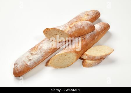 Nahaufnahme von frisch gebackenen ganzen und geschnittenen Weizen-Baguettes, isoliert auf weißem Hintergrund. Hauptklammer. Handwerkliches Brotbackkonzept Stockfoto