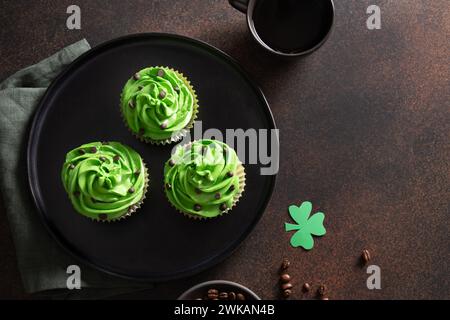 Drei Schokoladen-Cupcakes mit Kaffee und Schokoladenstreuseln auf braunem Hintergrund. St. Patrick's Day. Kopierbereich. Blick von oben. Stockfoto