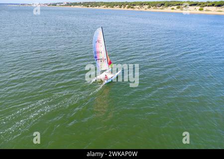 El Portil, Spanien-17. februar 2024: Drohnenansicht eines Katamaransegels im türkisfarbenen Wasser des El Portil Beach in Punta Umbri Stockfoto