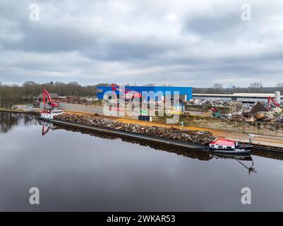 ALMELO, NIEDERLANDE - 17. FEBRUAR 2024: Schrottverarbeitungsunternehmen entlang eines Kanals mit einem Schiff voller Metallschrott Stockfoto