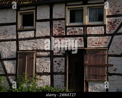 Details eines Fachwerkhauses, das renovierungsbedürftig ist, im Laufe der Jahrhunderte waren die Balken schief. Weiße Steinmauer, die Farbe blättert ab, die R Stockfoto