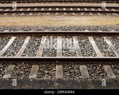 Eisenbahngleise als abstrakter Hintergrund. Seitlicher Blick auf die Stahlschienen und die Steine zwischen den Betonbindern. Stockfoto