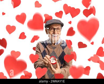 Ein älterer Mann zeigt einen Verlobungsring in einer Kiste und steht unter roten Herzen isoliert auf weißem Hintergrund Stockfoto
