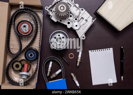 Verschiedene Autoteile mit einem Block und einem Kugelschreiber auf einem Arbeitstisch. Stockfoto