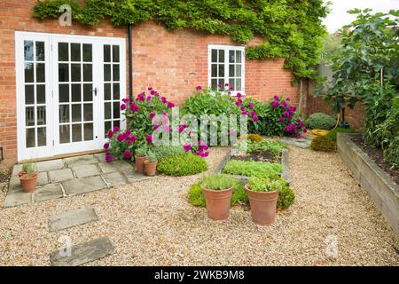 Britisches Haus und Garten mit Terrasse und Glastüren. Cottage oder Innenhof Garten (Hinterhof) mit Kies und Yorker Steinpflaster Stockfoto