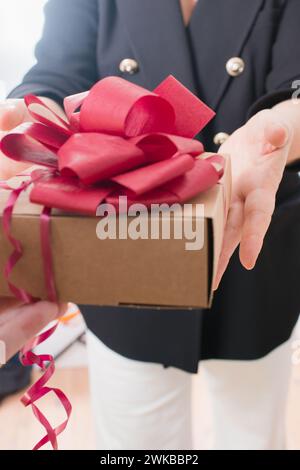 Reife Frau bekommt ein Geschenk mit rotem Band. Weißer Hintergrund Stockfoto