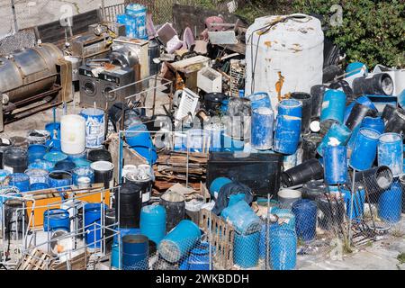 Ein Haufen von gruseligen Industrieabfallfässern, Müll und Schutt auf einem offenen Grundstück im Freien. Stockfoto