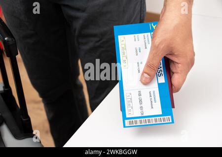 Nicht erkennbare Person, die zu Hause eine Bordkarte der Fluggesellschaft vorhält Stockfoto