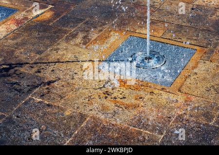 Städtischer Brunnen mit spritzendem Wasser vom Bürgersteig Stockfoto