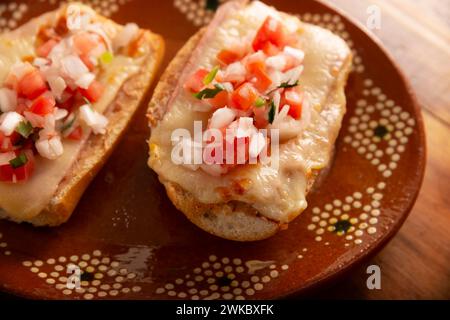 Molleten. Mexikanisches Rezept basierend auf Bolillo-Brot, das längs geteilt wird, mit gebratenen Bohnen und Gratin-Käse bestrichen wird, mit Pico de gallo-Sauce und etwas Pro Stockfoto