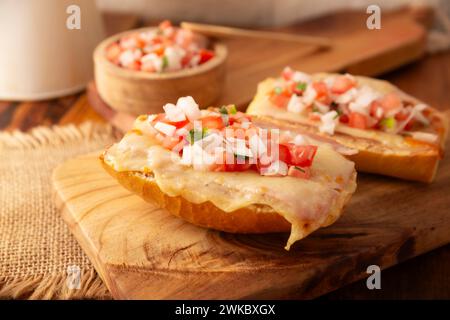 Molleten. Mexikanisches Rezept basierend auf Bolillo-Brot, das längs geteilt wird, mit gebratenen Bohnen und Gratin-Käse bestrichen wird, mit Pico de gallo-Sauce und etwas Pro Stockfoto