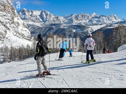 Skifahrer auf einer Piste vor den schneebedeckten Gebirgszügen der Dolomiten, Wintersportort Colfosco, Colfosco, Skigebiet Alta Badia Stockfoto