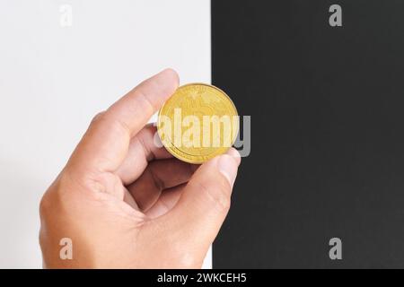 Bitcoin Halving-Konzept in Kryptowährung. Menschliche Hand, die Münze auf schwarz-weißem Hintergrund hält. Stockfoto