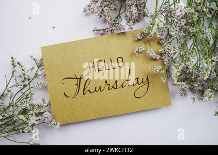 Hallo Donnerstag geschrieben auf Papierkarte mit Blumenrahmen auf rosa Hintergrund Stockfoto