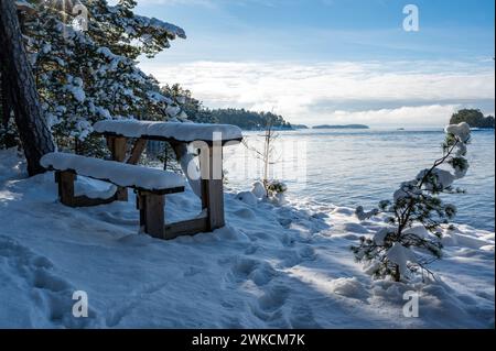 Bank und kleiner Tisch mit Blick auf den See Vattern Motala Schweden Stockfoto