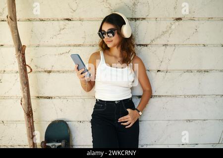 Porträt eines lächelnden Mädchens, das Musik aus der Playlist auf ihrem Handy hört Stockfoto