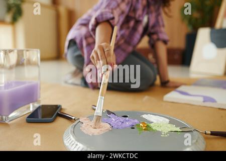 Mädchen, das Farbe auf dem Pinsel aufnimmt, während sie in ihrem Atelier arbeitet Stockfoto