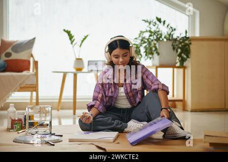 Talentiertes kreatives Mädchen, das Bilder in ihrem Schlafzimmer schmerzt und Musik hört Stockfoto
