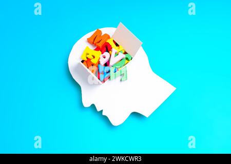 Der Kopf des Menschen ist in Papierform geschnitten und hat ein offenes Fenster, das eine Reihe von leuchtenden, bunten Buchstaben zeigt. Bildung und kreativer Geist Stockfoto