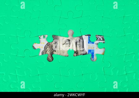 Puzzle-Hintergrund, der einige Teile von 100-Dollar-Scheinen durch die leeren Räume enthüllt. Finanzplanung, Investitionen und Vermögensverwaltung Stockfoto