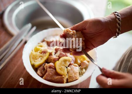 Eine Person bereitet marinierte Kebabs auf Spießen für ein Sommergrillen im Hinterhof vor, die in Nahaufnahmen aufgenommen werden. Stockfoto