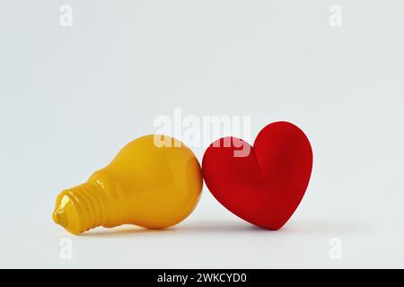 Gelbe Glühbirne mit Herz auf weißem Hintergrund - Konzept der Herz-Hirn-Verbindung Stockfoto