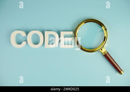Code-Buchstaben mit Lupe auf blauem Hintergrund Stockfoto