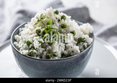 Jasminreis mit Erbsen und Petersilie in einer Schüssel auf dem Tisch. Stockfoto