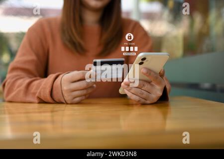 Junge Frau mit Kreditkarte und Eingabe des Verifizierungscodes auf das Online-Bankkonto Stockfoto