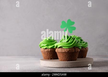 St. Patrick's Day leckere drei hausgemachte Cupcakes mit grüner Schlagsahne, dekoriert mit Schamrock und Klee auf grauem Hintergrund. Kopierbereich. Nahaufnahme. Stockfoto