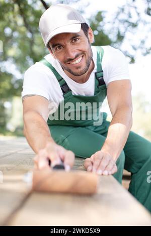 Happy man malt mit weißer Farbe auf Holzdielen Stockfoto