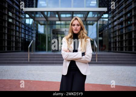 Porträt befähigte blonde schöne Frau im Anzug posiert selbstbewusst und sieht ernst aus bei der Kamera im Freien Stockfoto