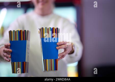 Ein Verkäufer steht vor dem Kino und hält frisches Popcorn, um es an Kinobesucher zu verkaufen, bevor sie das Kino betreten Stockfoto