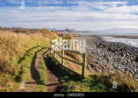 Blick nach Osten entlang des walisischen Küstenweges entlang der Küste mit Menschen, die von Criccieth, Llyn Peninsula, Gwynedd, Nordwales, Großbritannien, laufen, Großbritannien Stockfoto