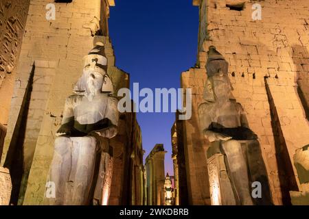 Kolossale Statuen von Ramses II (Ramses II) im Tempel von Luxor, beleuchtet bei Nacht, in Luxor, Ägypten Stockfoto