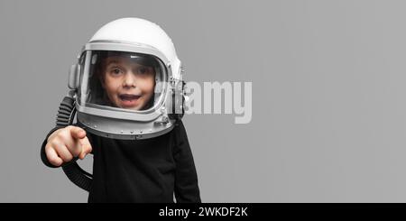 Ein kleines Kind möchte mit einem Astronautenhelm im Weltraum fliegen, auf dem üppigen Lavabackground Stockfoto