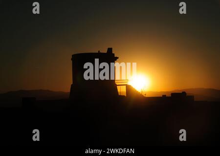 Die Sonne untergeht hinter dem Torreon de San Miguel del Cabo de Gata und wirft eine dramatische Silhouette über den orangen Himmel Stockfoto