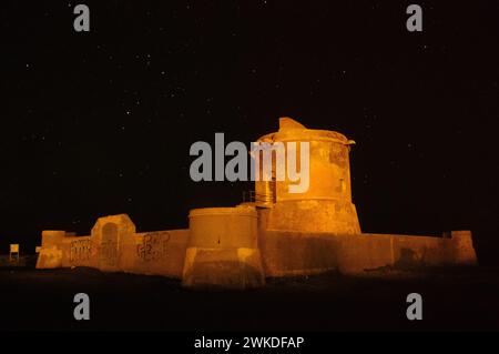 Nächtlicher Blick auf den Torreon de San Miguel del Cabo de Gata im warmen Licht, mit einer Kulisse des sternenbesetzten Himmels Stockfoto