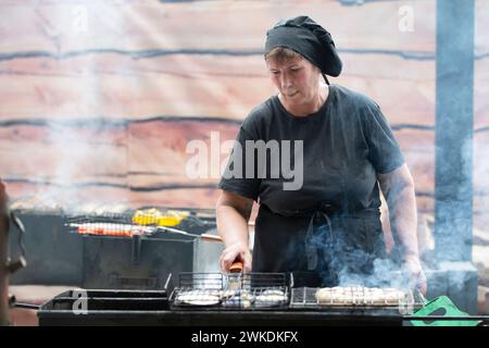 Juni 2023. Weißrussisches Dorf Aftyuk, Urlaub auf der Straße. Eine Küchenchefin bereitet Schaschlik in Rauch und Hitze zu. Stockfoto