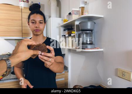 Nahaufnahme der männlichen Hand, die ein Stück Kuchen von einem anderen Mann nimmt, der in der Küche steht, mit Kopierraum, Lebensstil und Menschenkonzept, erste Person. Stockfoto