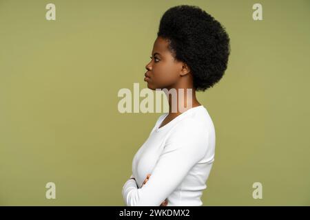 Afroamerikanerin posiert mit Seitenansicht und überkreuzten Armen, isoliert auf grünem Studiohintergrund Stockfoto
