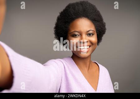 Nahaufnahme fröhliche schwarze Frau, die Selfie macht, isoliert auf grauem Studiohintergrund Stockfoto